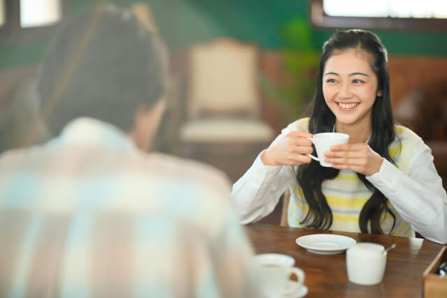 コーヒーカップを持って笑顔で話す女性