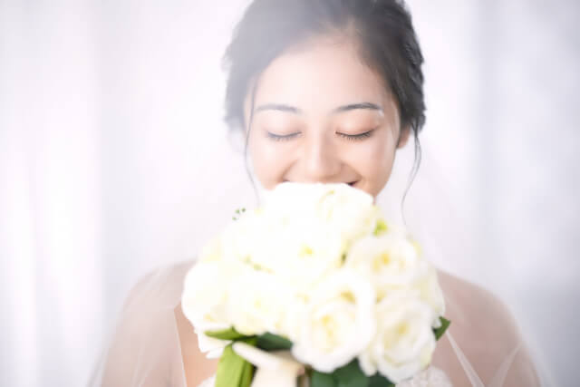 白いブーケの香りを楽しむ花嫁